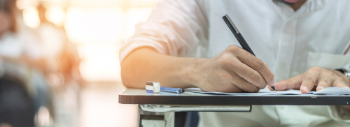 Etudiant, rebord d'une table sur la quelle il s'appuie pour compléter son examen final